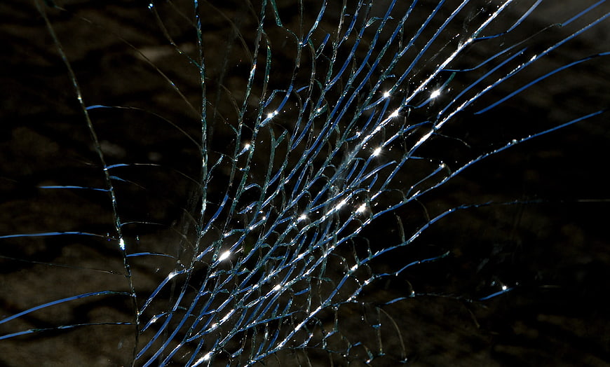 Close-up of shattered glass with blue reflections and bright highlights