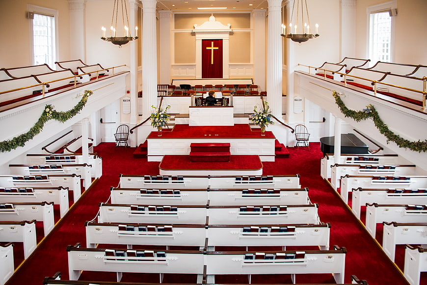 Interior of a traditional church with red carpet and white pews