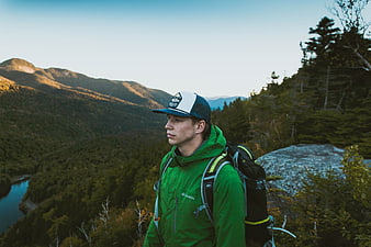 Young Hiker in Green Jacket Looking at Mountain Landscape