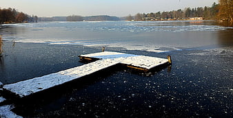 Snow-covered wooden dock on a frozen lake in winter