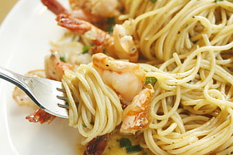 Close-up of shrimp spaghetti with fork and herbs