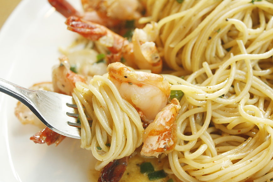 Close-up of shrimp spaghetti with fork and herbs