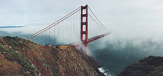 Golden Gate Bridge emerging from thick fog on a cloudy day