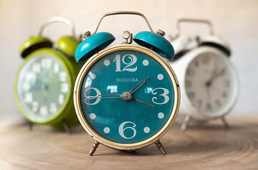 Vintage teal alarm clock on wooden surface with blurred background