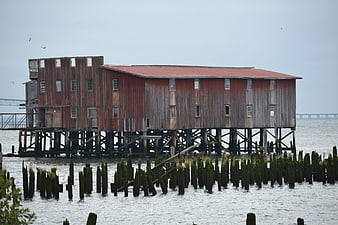 Abandoned red wooden building on stilts over water