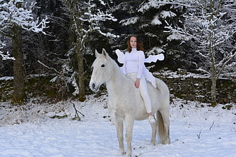 Woman with Fairy Wings Riding White Horse in Snowy Forest
