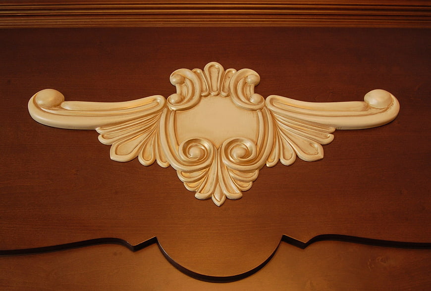 Ornate Cream Rococo Wood Carving on Brown Furniture