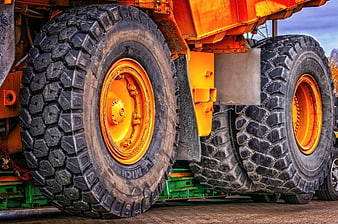 Close-up of heavy construction vehicle tires and orange chassis