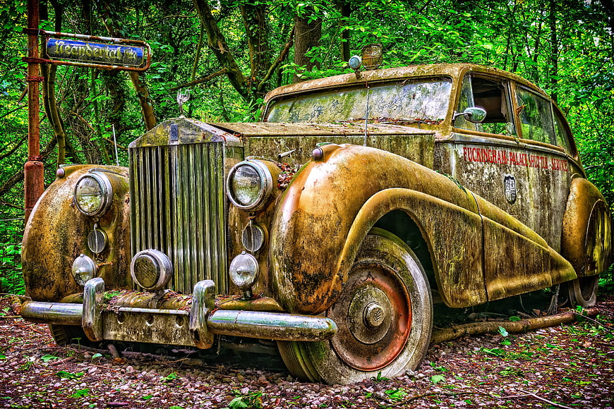 Abandoned vintage Rolls Royce in overgrown forest