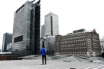 Man in Blue Jacket Standing on Rooftop Looking at City Skyline
