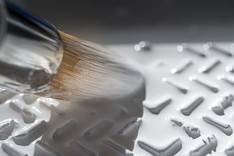 Close-up of paintbrush applying white paint on metal surface