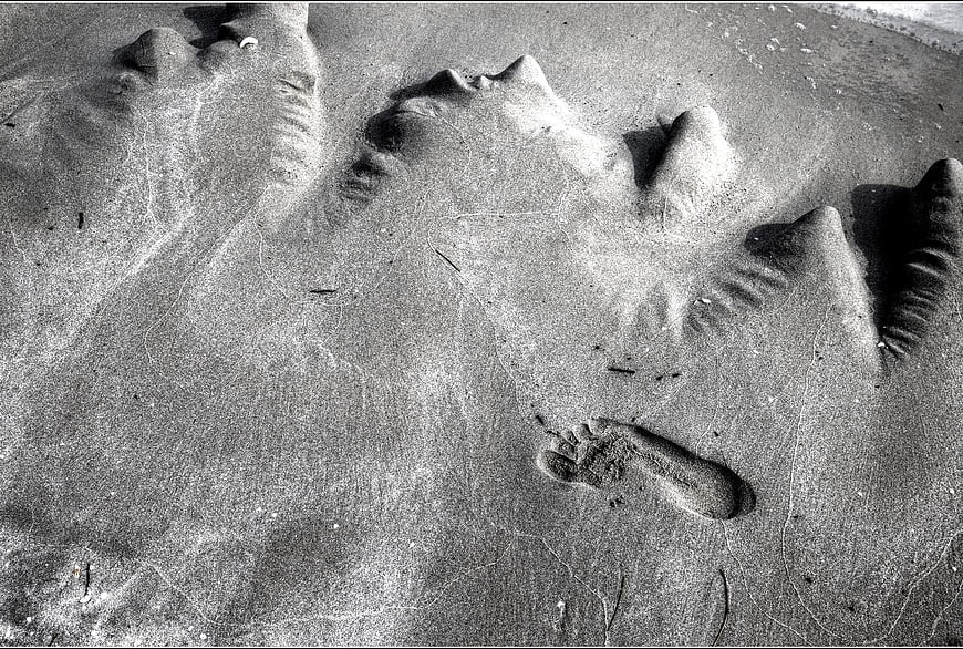 Black and white footprint in textured sand on a beach