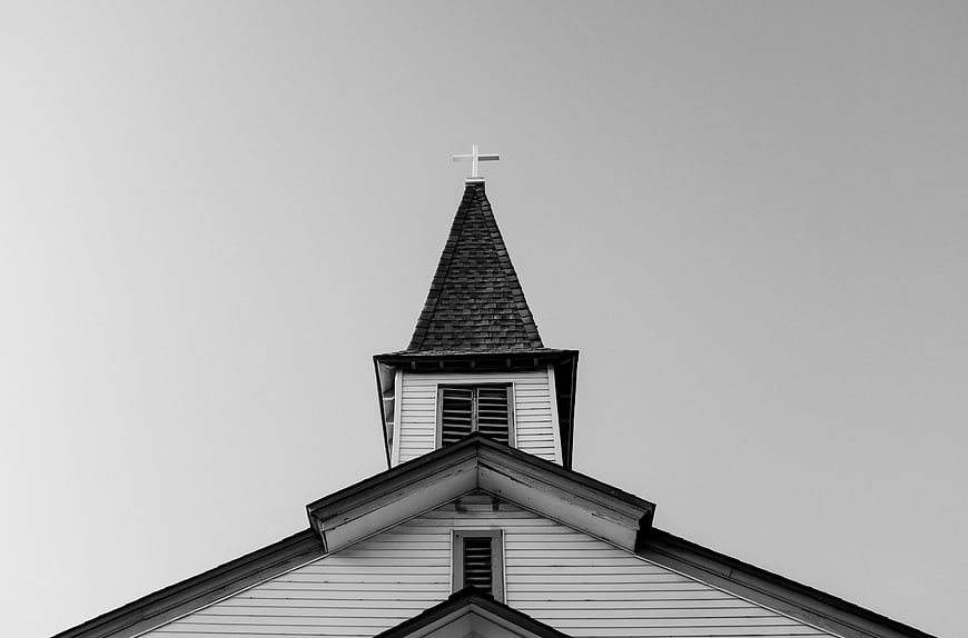 Black and white church steeple with cross against sky