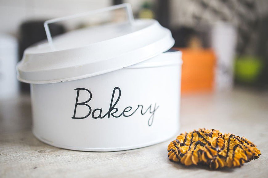 White Bakery Tin with Cookie on Wooden Table