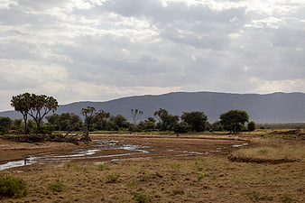 Dry African Riverbed with Mountains and Cloudy Sky
