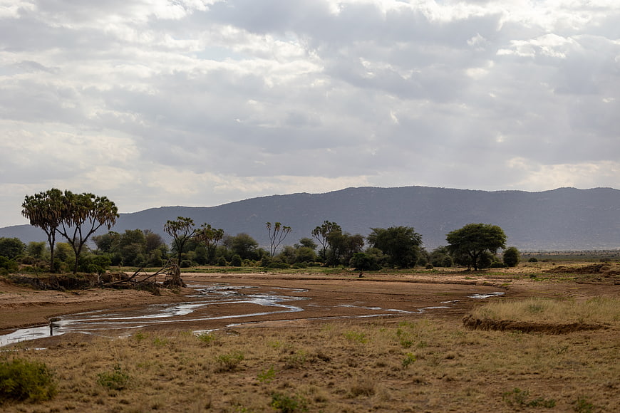 Dry African Riverbed with Mountains and Cloudy Sky