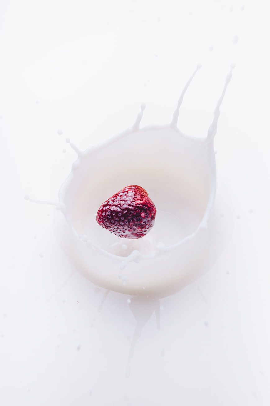 Fresh Strawberry Dropping into Milk Splash