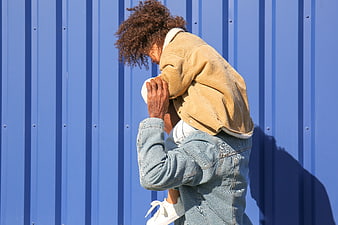 Father carrying daughter on shoulders against blue wall