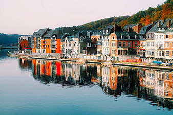Colorful waterfront buildings reflecting in calm river, Dinant Belgium
