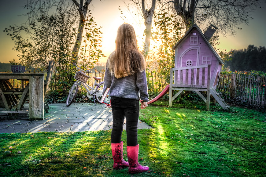 Little Girl in Pink Boots Standing in Garden at Sunset