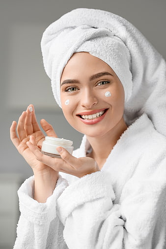 Happy Woman Applying Face Cream in White Bathrobe