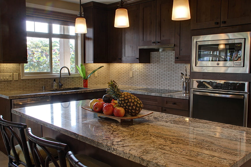 Modern kitchen with granite island, fruit bowl, and dark wood cabinets