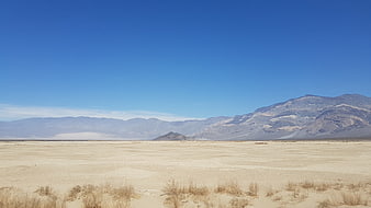 Vast desert landscape with mountains under clear blue sky