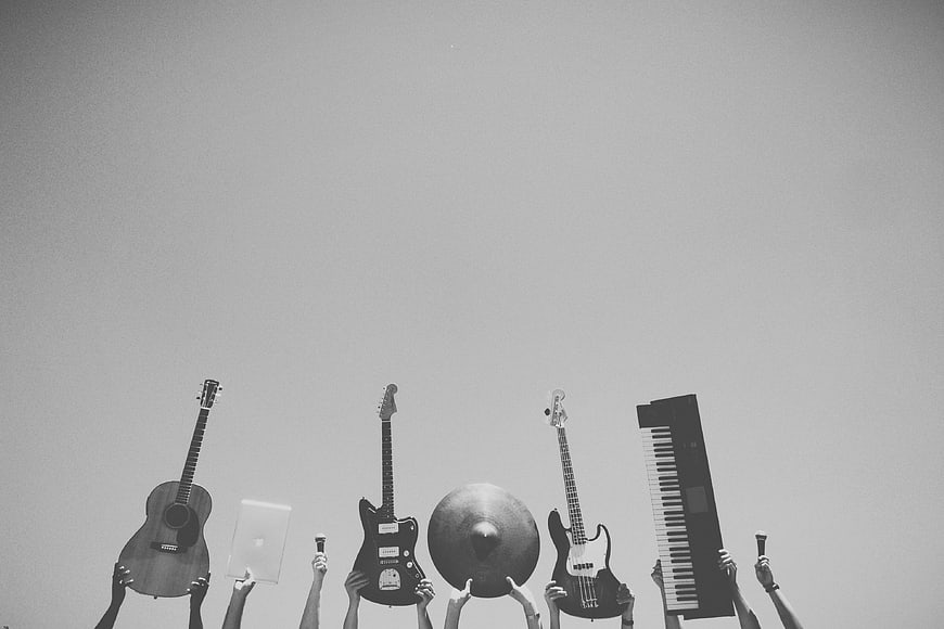 Hands holding musical instruments against sky background