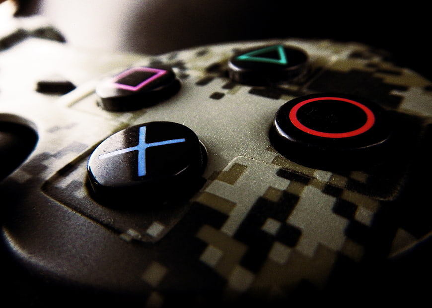 Close-up of PlayStation controller buttons with digital camouflage pattern