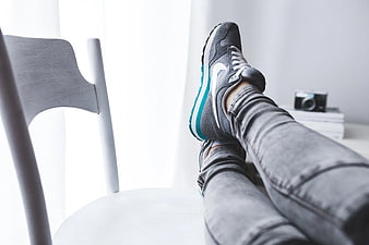 Woman resting legs in sneakers on white chair