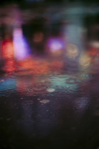 Abstract colorful rain ripples on wet city street at night