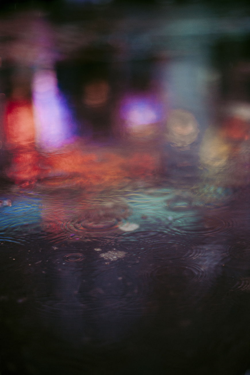 Abstract colorful rain ripples on wet city street at night