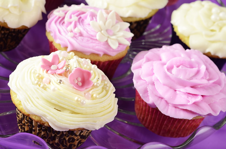 Decorated pink and white cupcakes on purple glass stand