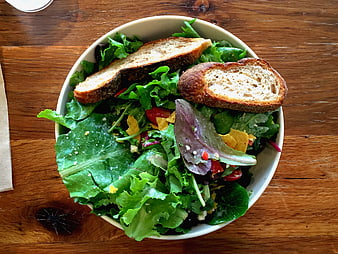 Fresh green salad with toasted bread on wooden table