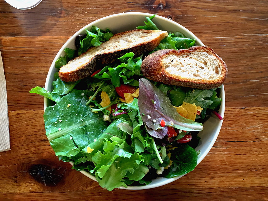 Fresh green salad with toasted bread on wooden table