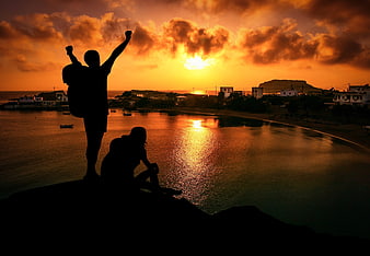 Silhouetted Hikers Celebrating Sunset Over Coastal Village
