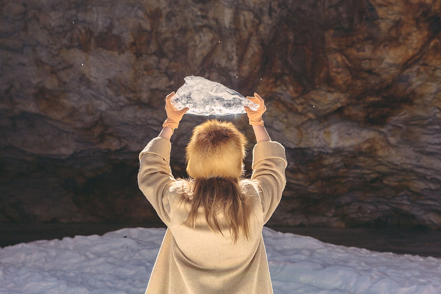 Woman holding glowing ice crystal in winter cave