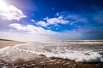 Sandy Beach with Ocean Waves and Blue Sky