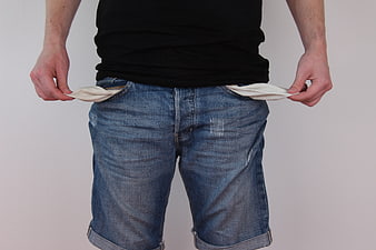 Man turning out empty pockets in jeans symbolizing poverty