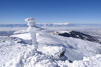Snow-covered mountain summit with ice formation and valley view