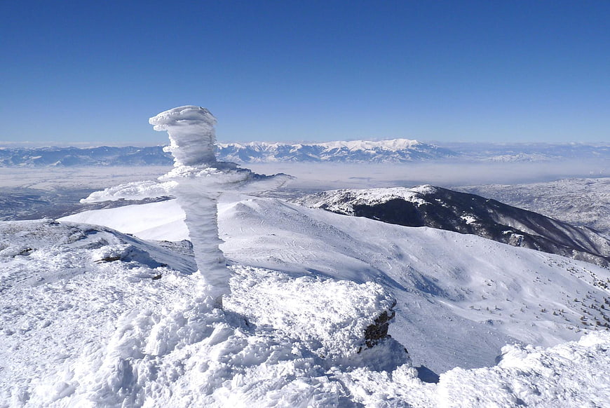 Snow-covered mountain summit with ice formation and valley view