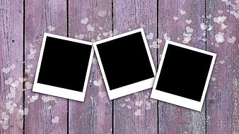 Three empty polaroid frames on purple wooden background with heart bokeh