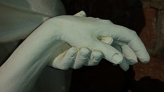 Close-up of white stone hands clasped together in prayer