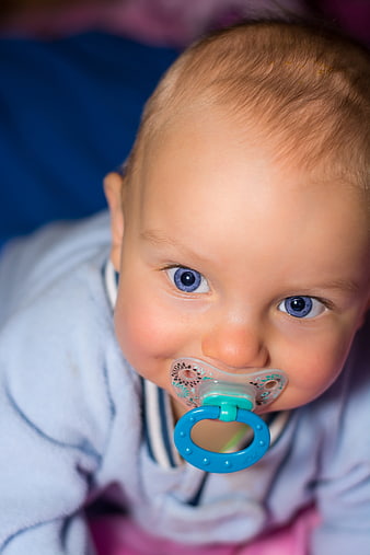 Close-up portrait of baby with blue eyes and pacifier