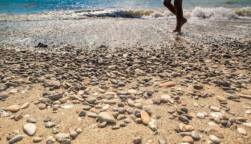 Low angle view of pebbles on sandy beach with walking legs