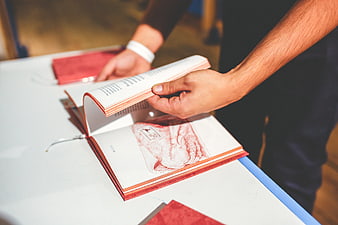 Man flipping through a red book on a white table