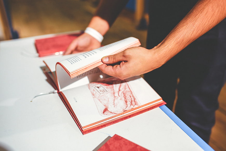 Man flipping through a red book on a white table