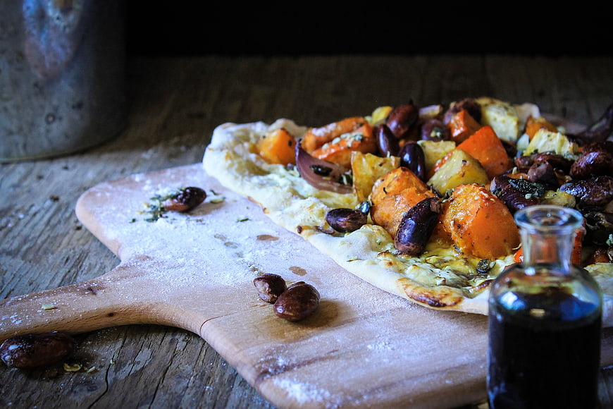 Rustic pumpkin tart with olives on wooden board