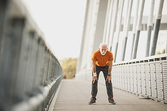 Senior man resting after running on a modern bridge