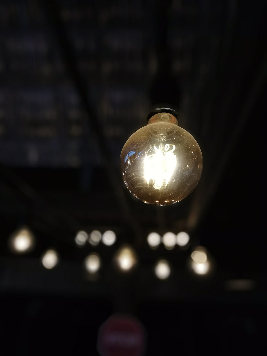 Glowing Vintage Light Bulb Hanging in Dark Room